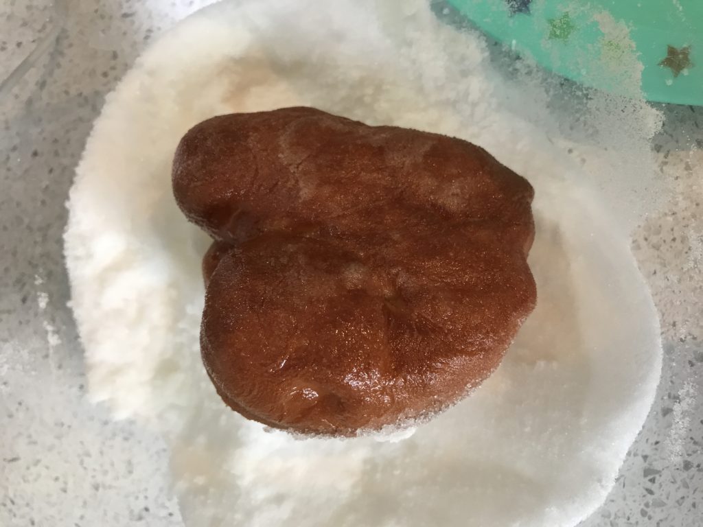 Rolling doughnut in sugar